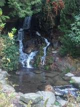 Picture of a pool of water surrounded by rocks and greenery in the foreground with a double waterfall in the background